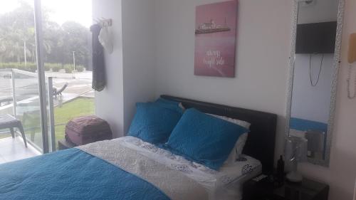 a bedroom with a bed with blue pillows and a window at Apartamento en BalaBeach María Chiquita in front of the beach 2hab in Colón