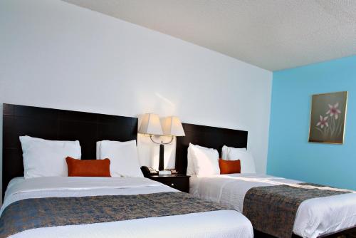 two beds in a hotel room with blue walls at Coratel Inn & Suites by Jasper Newton in Newton