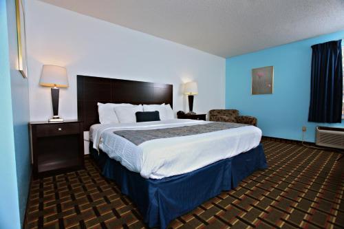 a hotel room with a large bed with blue walls at Coratel Inn & Suites by Jasper Newton in Newton