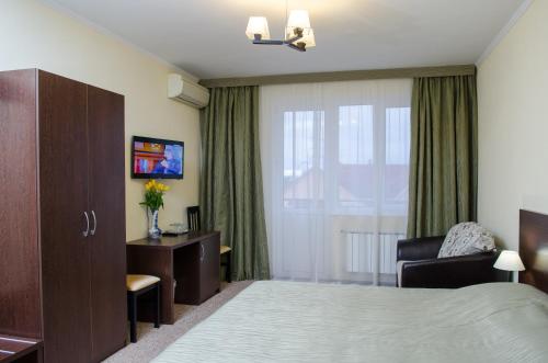 a hotel room with a bed and a chair and a window at Guest House Topaz in Adler