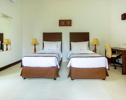 two beds sitting in a room with a desk at Amaluna Resorts in Negombo