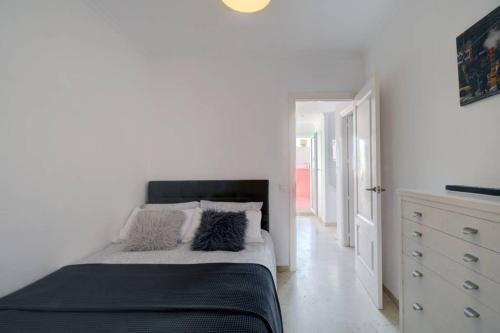 a white bedroom with a bed and a dresser at Duplex con vistas al mar in La Línea de la Concepción