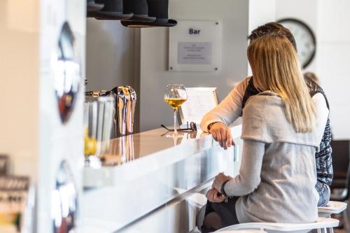 a woman sitting at a bar with a glass of wine at Holiday Inn Express Dijon, an IHG Hotel in Dijon