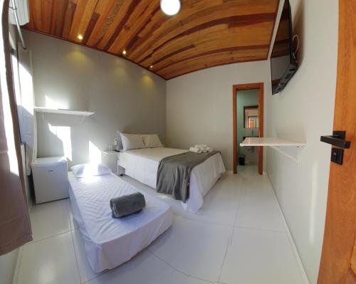 a bedroom with two beds and a wooden ceiling at Pousada Mirai -Centro- in Arraial do Cabo