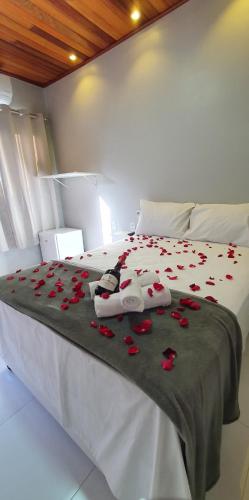 a white bed with red roses on it at Pousada Mirai -Centro- in Arraial do Cabo