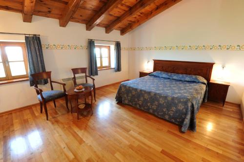 
a bedroom with a bed, chair, table and a window at Belica Bed and Breakfast in Dobrovo
