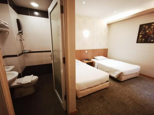 a hotel room with two beds and a toilet at Prescott Hotel Bukit Bintang in Kuala Lumpur