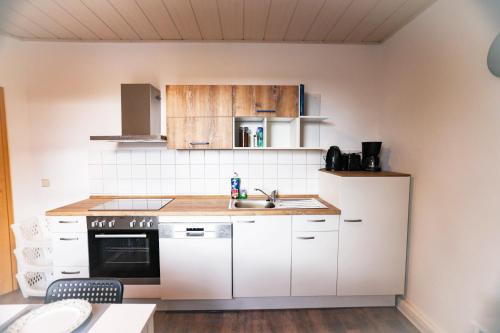 a kitchen with white cabinets and a sink at cosy apartment in Neupetershain with Wifi in Neupetershain