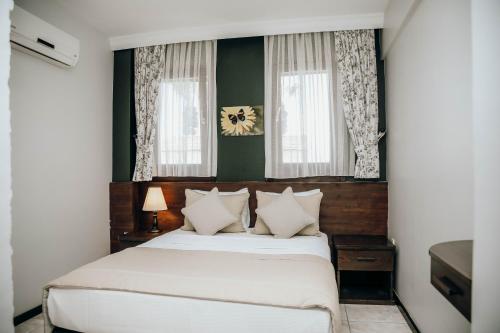 1 dormitorio con 1 cama blanca y 2 ventanas en Mandalin Pansiyon, en Siğacık