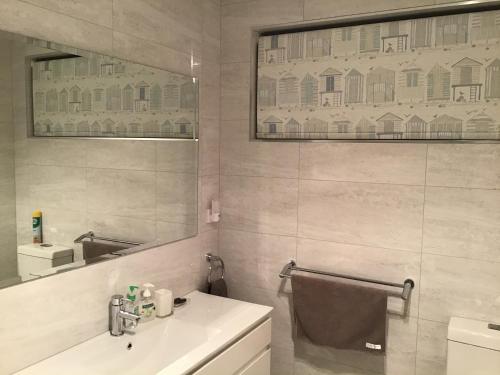 een witte badkamer met een wastafel en een spiegel bij Swansea Beach House Oceanfront in Swansea