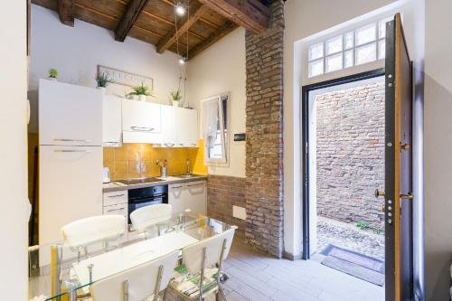 a kitchen with white cabinets and a brick wall at Nel cuore di Ferrara in Ferrara
