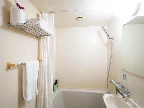 een badkamer met een wit bad en een wastafel bij Hotel AreaOne Nobeoka in Nobeoka