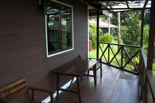 a porch with two benches and a table and a window at 1511 Coconut Grove in Tioman Island