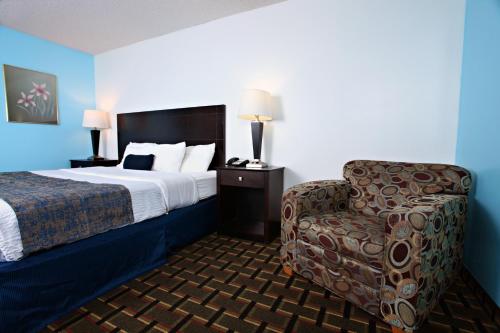 a hotel room with a bed and a chair at Coratel Inn & Suites by Jasper Newton in Newton