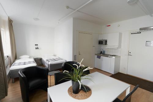 a living room with a table and chairs and a kitchen at Slagsta Gate Hotell in Norsborg