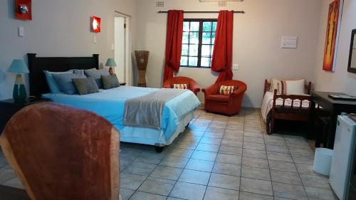 1 dormitorio con 1 cama, 2 sillas y escritorio en Parkers Cottages, en St Lucia