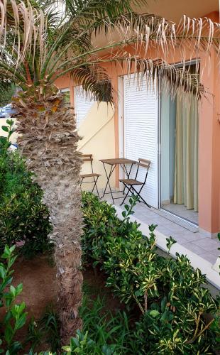 a palm tree in front of a house with a table at Yms studios in Rethymno Town