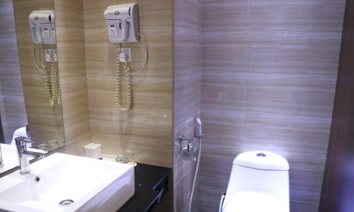 a bathroom with a toilet and a sink and a phone at Aston Inn Gideon Batam in Nagoya