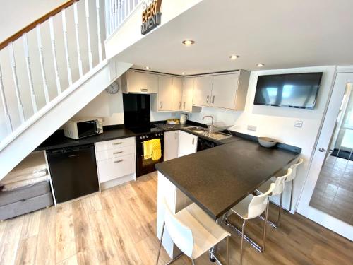 a kitchen with white cabinets and a staircase at Sunsets In Porthtowan, Cornwall Coastal Holidays in Porthtowan