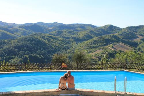 two people sitting next to a swimming pool with a camera at Country House Il Biroccio in Urbino