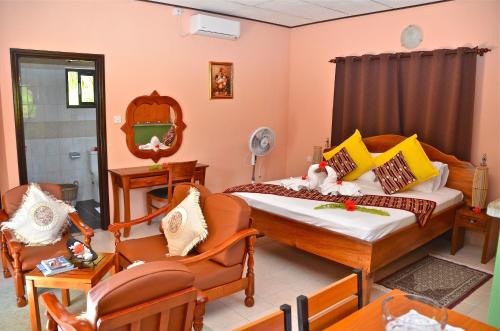 a bedroom with two beds and chairs and a tv at My Angel in La Digue