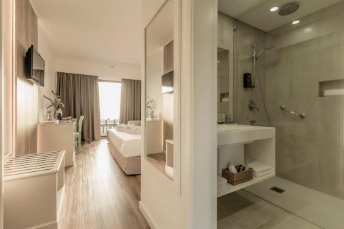 a bathroom with a shower and a sink and a bed at Caloura Hotel Resort in Caloura