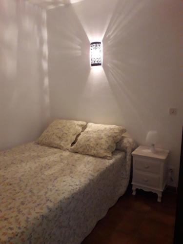 Un dormitorio con una cama y una luz en la pared. en Appartement calme à deux pas de la mer, en Saintes-Maries-de-la-Mer
