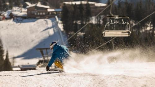 a man riding a snowboard down a snow covered slope at Piano Annaberg Apartments in Annaberg