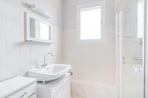 La salle de bains blanche est pourvue d'un lavabo et d'une douche. dans l'établissement Bocage, à Cersay