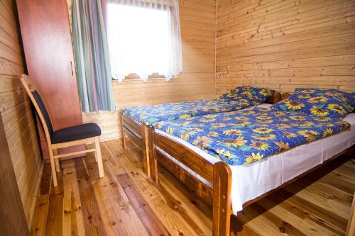 a bedroom with a bed and a chair in a cabin at Zacisze pod Laskiem in Karwieńskie Błoto Pierwsze