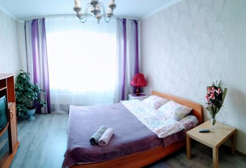 オムスクにあるApartment on prospekt Komarova 31のベッドルーム1室(ベッド1台、テーブル、窓付)