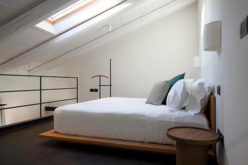 a bedroom with a white bed and a wooden table at Dai Gresy - In Langa in Treiso