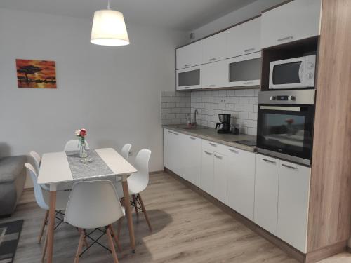 kuchnia z białymi szafkami, stołem i krzesłami w obiekcie Hatvan Corner Apartments w Debreczynie