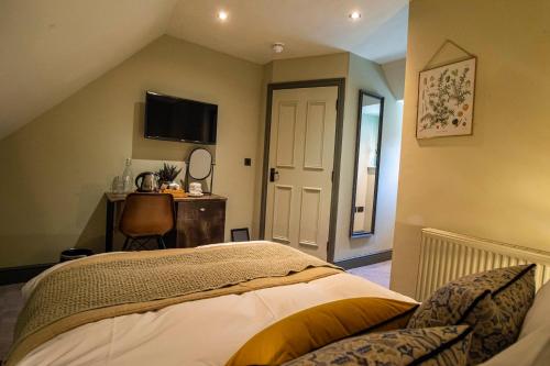a bedroom with a bed and a desk and a television at Kings Arms Hotel in Stansted Mountfitchet