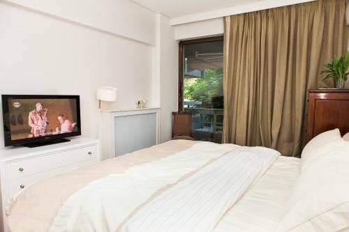 Schlafzimmer mit einem weißen Bett und einem TV in der Unterkunft Delux Apartment with Amazing Balcony! in Athen