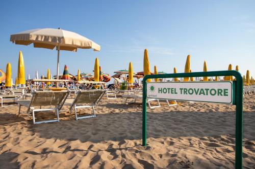 un cartello su una spiaggia con sedie e ombrelloni di Hotel Trovatore a Lido di Jesolo