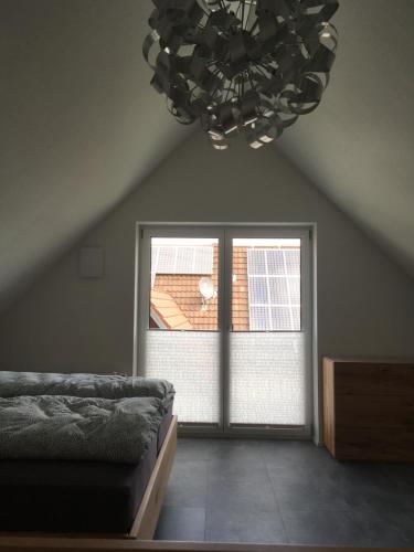 a bedroom with a chandelier and a large window at Zeitfrei-Apartments in Kirchheim unter Teck