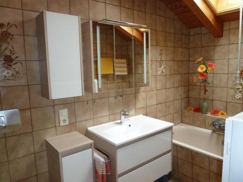 een badkamer met een wastafel, een spiegel en een bad bij Ferienwohnung Burgenblick in Hopferau