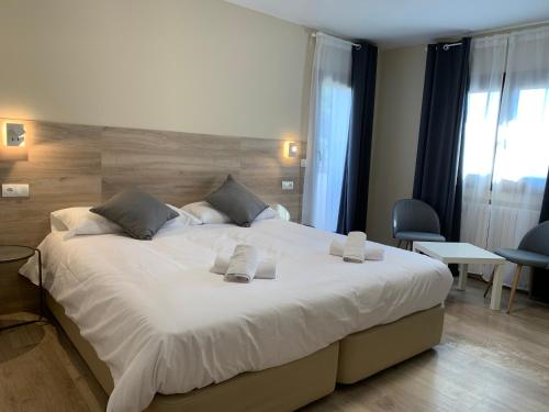 a bedroom with a large bed with white sheets at Hotel El Cobertizo in Plasencia del Monte