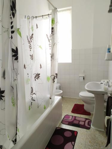 a bathroom with a toilet and a shower curtain with butterflies at Pensión Luisito in Santander