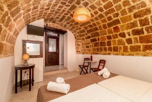 ein Schlafzimmer mit einem Bett und einer Steinmauer in der Unterkunft Auberge 32 Old Town in Rhodos (Stadt)