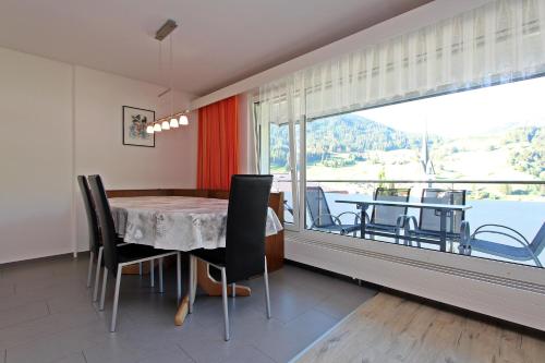 a dining room with a table and chairs and a large window at Tgesa La Niva 11 in Savognin