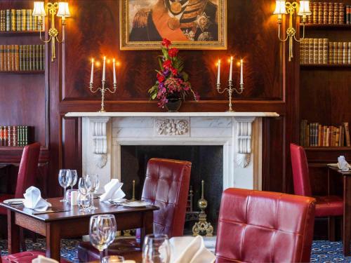 a dining room with tables and chairs and a fireplace at Exeter Rougemont Hotel by Sunday in Exeter