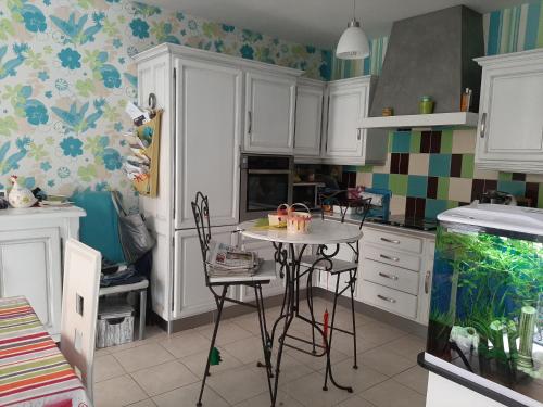 une cuisine avec des placards blancs et une petite table dans l'établissement La Palatine chambre chez l habitant à 20 mn de Rodez, à Calmont