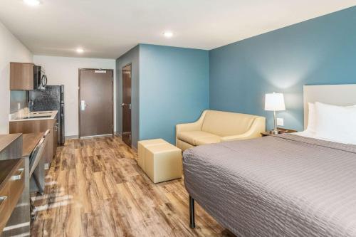 a bedroom with a bed and a chair and a kitchen at WoodSpring Suites Greenville Haywood Mall in Greenville