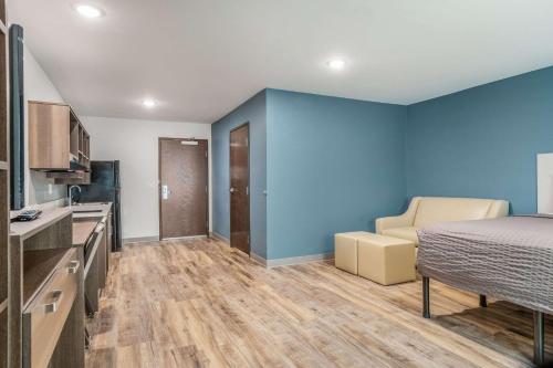 a room with a bed and a couch and a kitchen at WoodSpring Suites Greenville Haywood Mall in Greenville
