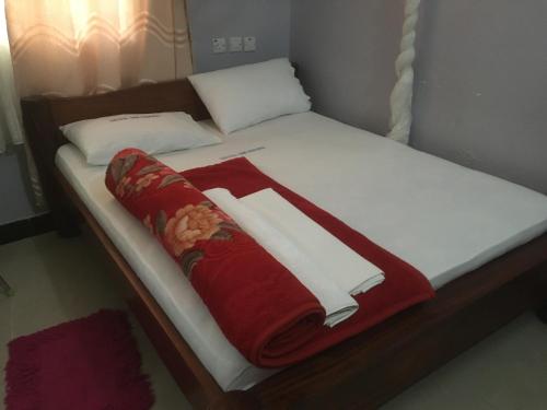 a bed with a red and white blanket on it at Dodoma Siesta Inn in Dodoma