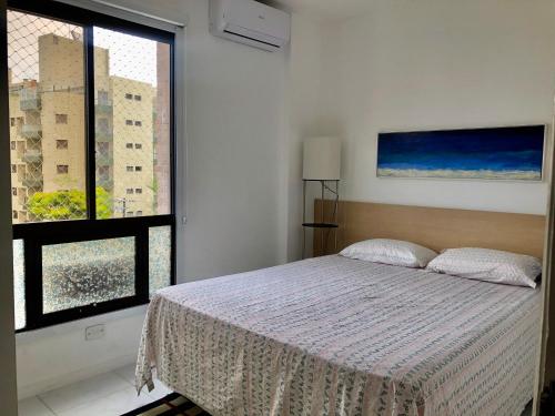 a bedroom with a bed and a large window at Ap Riviera uma quadra da praia in Bertioga