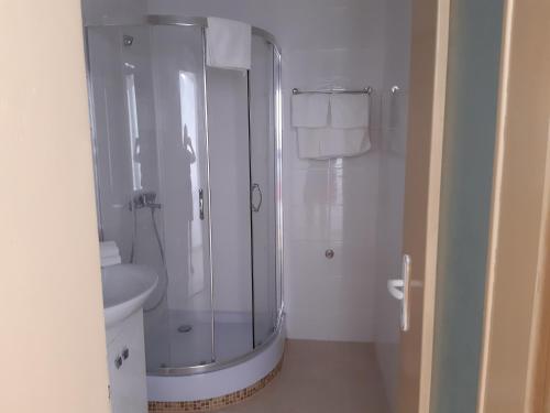 La salle de bains est pourvue d'une douche en verre et de toilettes. dans l'établissement Aparthotel Romance, à Kiten