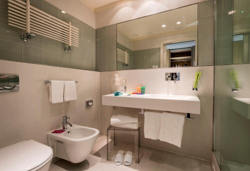a bathroom with a sink and a toilet and a mirror at Devero Hotel & Spa, BW Signature Collection in Cavenago di Brianza